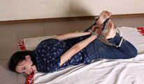 Emily in violet short-sleeve and jeans, hog-cuffed with steel cuffs, wiggles on the floor