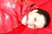 Lucy tied, gagged and hooded on a bed wearing a sexy black shiny nylon pants and a red down jacket (Pics)