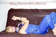 PIA tied and gagged with a pillory on a sofa wearing a sexy blue really shiny nylon rain bib overall (Pics)