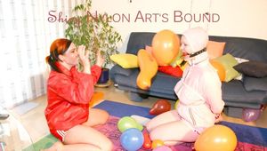 Jill ties and gagges an archive girl on the floor in the middle of balloons both wearing sexy shiny nylon shorts and rain jackets (Pics)