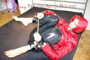Pia tied and gagged with a bar on bed wearing a supershiny black down pants and a red down jacket (Pics)