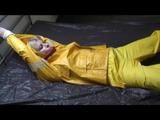 Pia tied and gagged in an yellow rainsuit on bed (Video)