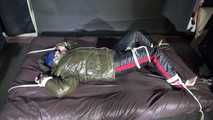 Watching Jill being tied on a bed wearing a shiny nylon rain jacket and a down jacket as well as a rain pants being double hooded and gagged with a ballgag (Video)