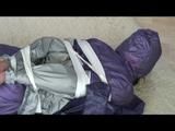 A video with Alina tied and gagged in a shiny purple and silver PVC suit