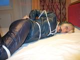 One of our beautiful archive girls in an blue rain suit tied and gagged in bed (pics)
