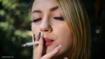 Blond lady is smoking white cigarette outdoors