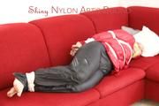 Jill tied, gagged and hooded on a red sofa wearing a black rainpants and a red rain jacket (Pics)