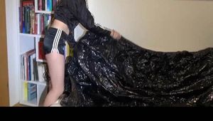 Mara tidying up the book shelf and lolling on the sofa wearing a black shiny nylon shorts and a black rain jacket (Video)