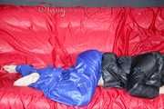 Sonja wearing a blue shiny nylon raver pants and a black down jacket posing and lollingn on the sofa (Pics)
