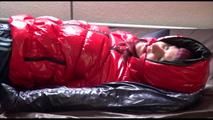 Mara tied, gagged and hooded on bed wearing s shiny red down jacket and a darkblue rain pants (Video)