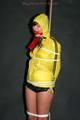 Alina tied and gagged to a pole in nylon shorts and yellow cagoule