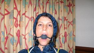 one of our archive girls tied and gagged in shiny nylon rainwear