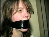 HEATHER IS F0RCED TO TAPE UP HER LEGS AND BARE FEET & IS THEN PANTY STUFFED AND WRAP GAGGED THEN HOG-TIED WITH TAPE ON THE BED (D52-14)