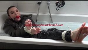 Jill tied and gagged in a bath tub wearing shiny nylon rain pants and a shiny down jacket (Video)