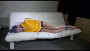 Mara with blue hairs wearing a sexy blue/yellow shiny nylon shorts and a yellow rain jacket tied and gagged with ropes and a ball gag on the sofa (Video)