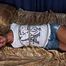 Barefoot Christy in white top and jeans shorts, hogtied with her elbows tied together, is tickled and teased by camera man