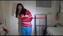 Mara tied, gagged and hooded in a laundry wearing a sexy blue down pants and a red down jacket (Video)