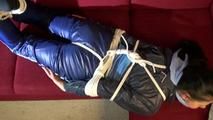 Lucy tied and gagged on a red sofa wearing a supersexy blue shiny nylon pants and a blue rain jacket (Video)