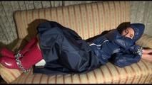 Mara tied, gagged and hooded on an old sofa wearing a cool blue rain skirt and a jacket as well as rubber boots (Video)