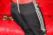 Sonja wearing a black rain pants and a red shiny nylon rain jacket tied and gagged with ropes overhead (Pics)