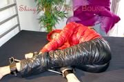 Pia tied and gagged with a bar on bed wearing a supershiny black down pants and a red down jacket (Pics)