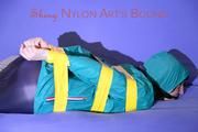 Mara tied and gagged with tape on a sofa wearing a supersexy shiny blue rain pants and a grren rain jacket (Pics) 