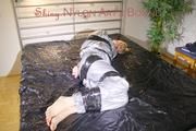 Pia tied and gagged with tape on a bed wearing a sexy silver rainwear combination (Pics) 