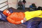 Pia tied and gagged on bed wearing a yellow rain pants and an orange downjacket (Pics)