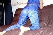 PIA tied and gagged with a pillory on a sofa wearing a sexy blue really shiny nylon rain bib overall (Pics)