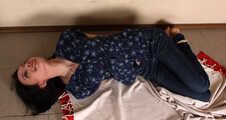 Emily in violet short-sleeve and jeans, hog-cuffed with steel cuffs, wiggles on the floor