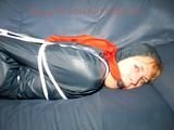 Leonie tied, gagged and hooded sitting on a sofa wearing a sexy shiny nylon shorts and a rain jacket (Pics)