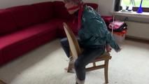 Mara tied and gagged on a chair with a bar wearing a sexy blue shiny nylon rain pants and a green rain jacket (Video)