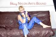 PIA tied and gagged with a pillory on a sofa wearing a sexy blue really shiny nylon rain bib overall (Pics)