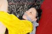 LUCY tied and gagged with ropes and a ballgag on a sofa wearing a sexy black/yellow shiny nylon shorts and a yellow rain jacket (Pics)