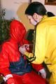 Jill tied by her friend in shiny yellow and red rainsuits