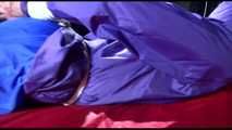 Sonja tied and gagged with ropes and a ballgag on a bed covered with a red shiny nylon cloth wearing a blue shiny nylon rain pants and a purple rain jacket (Video)