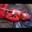 Pia tied and gagged on bed wearing a shiny red down jacket and a red rain pants (Video)