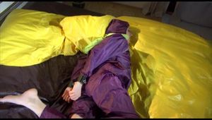 Lucy tied, gagged and hooded on bed on a bar wearing sexy purple rainwear (Video)