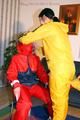 Jill tied by her friend in shiny yellow and red rainsuits