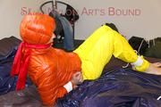 Pia tied and gagged on bed wearing a yellow rain pants and an orange downjacket (Pics)