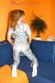 Leonie posing on a sofa wearing a grey adidas shiny nylon rainwear (Pics)