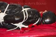 Lucy wearing a black shiny nylon rainh pants and a black down jacket tied and gagged on a sofa (Pics)