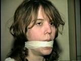HEATHER IS F0RCED TO TAPE UP HER LEGS AND BARE FEET & IS THEN PANTY STUFFED AND WRAP GAGGED THEN HOG-TIED WITH TAPE ON THE BED (D52-14)