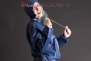 Mara posing in the studio wearing a blue rain skirt and a blue rain jacket as wellas red rubber boots (Pics)