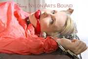 Mara tied and gagged with chains and cuffs on a bed wearing a superhot yellow shiny nylon shorts and an orange rain jacket (Pics)