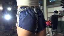 Watching sexy Sandra wearing an darkblue shiny nylon shorts and a white adidas top being tied and gagged overhead with ropes, chaines and a ballgag (Video)