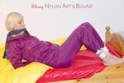 Pia in a shiny purple rainsuit tied and gagged in bed (Pics)