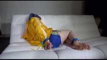Mara with blue hairs wearing a sexy blue/yellow shiny nylon shorts and a yellow rain jacket tied and gagged with ropes and a ball gag on the sofa (Video)