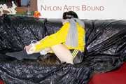 LUCY tied and gagged with ropes and a ballgag on a sofa wearing a sexy black/yellow shiny nylon shorts and a yellow rain jacket (Pics)