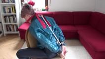 Mara tied and gagged on a chair with a bar wearing a sexy blue shiny nylon rain pants and a green rain jacket (Video)